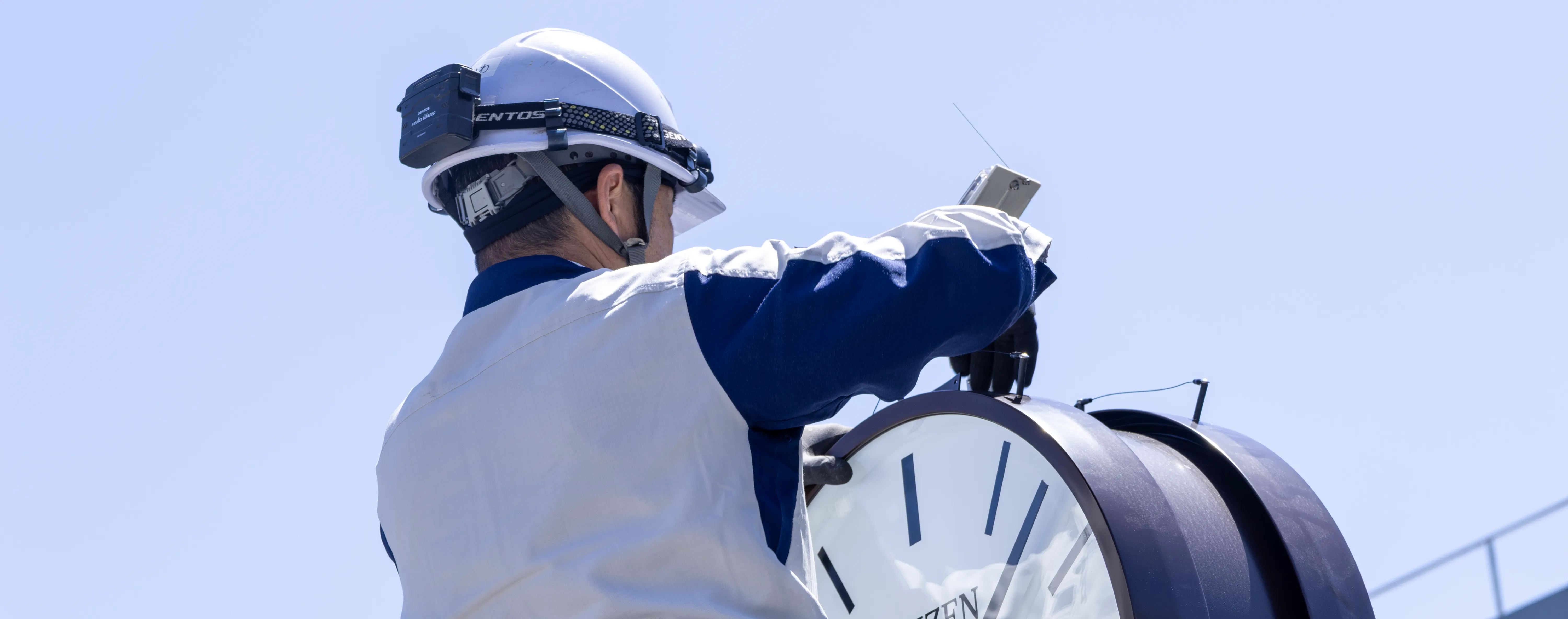 屋外時計を修理している技術員